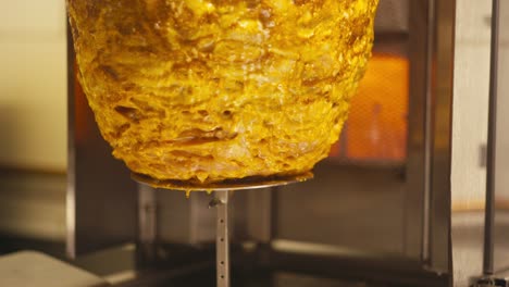 juicy kebab meat rotating on a skewer in a warm, glowing kebab shop