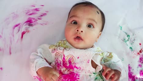 infant paying holi in traditional dress with colors from top angle