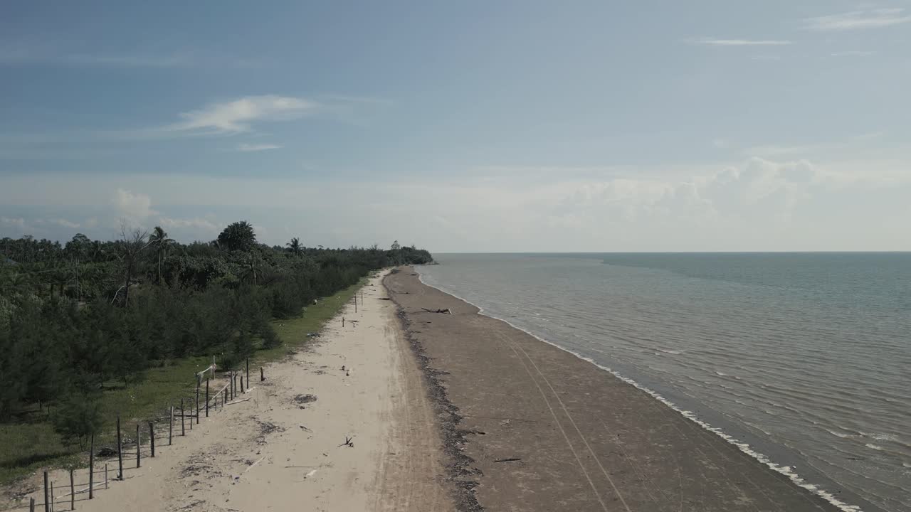 Vista aerea con drone durante l'estate del villaggio di pescatori di Alit, Kabong, affacciato sul mare aperto e blu, con spiaggia di sabbia bianca, palme da cocco verdi e un fiume, Sarawak, Borneo