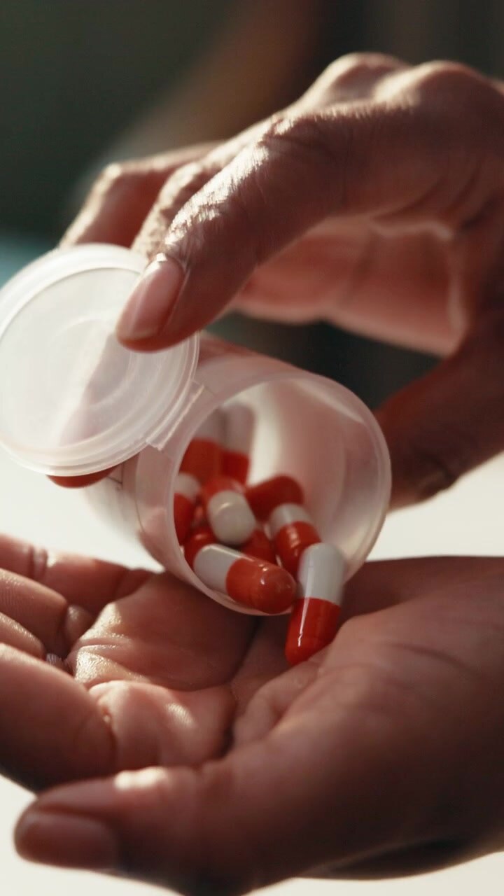 Person Pouring Prescription Capsules Into Hand