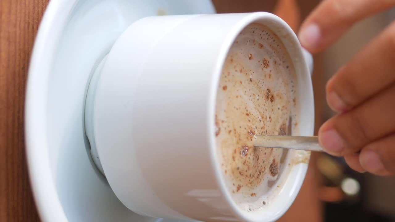 Close-up of a cup of cappuccino being stirred