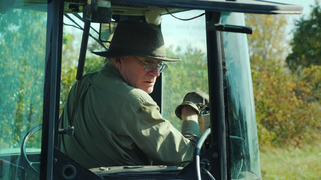 농부는 트랙터 캡에서 컨트롤을 조작합니다.