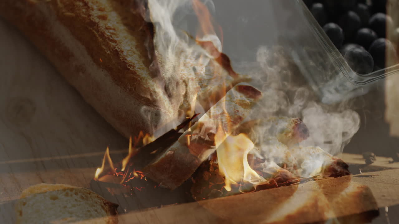 In kitchen, flames and smoke rising over bread and blueberries, creating animation