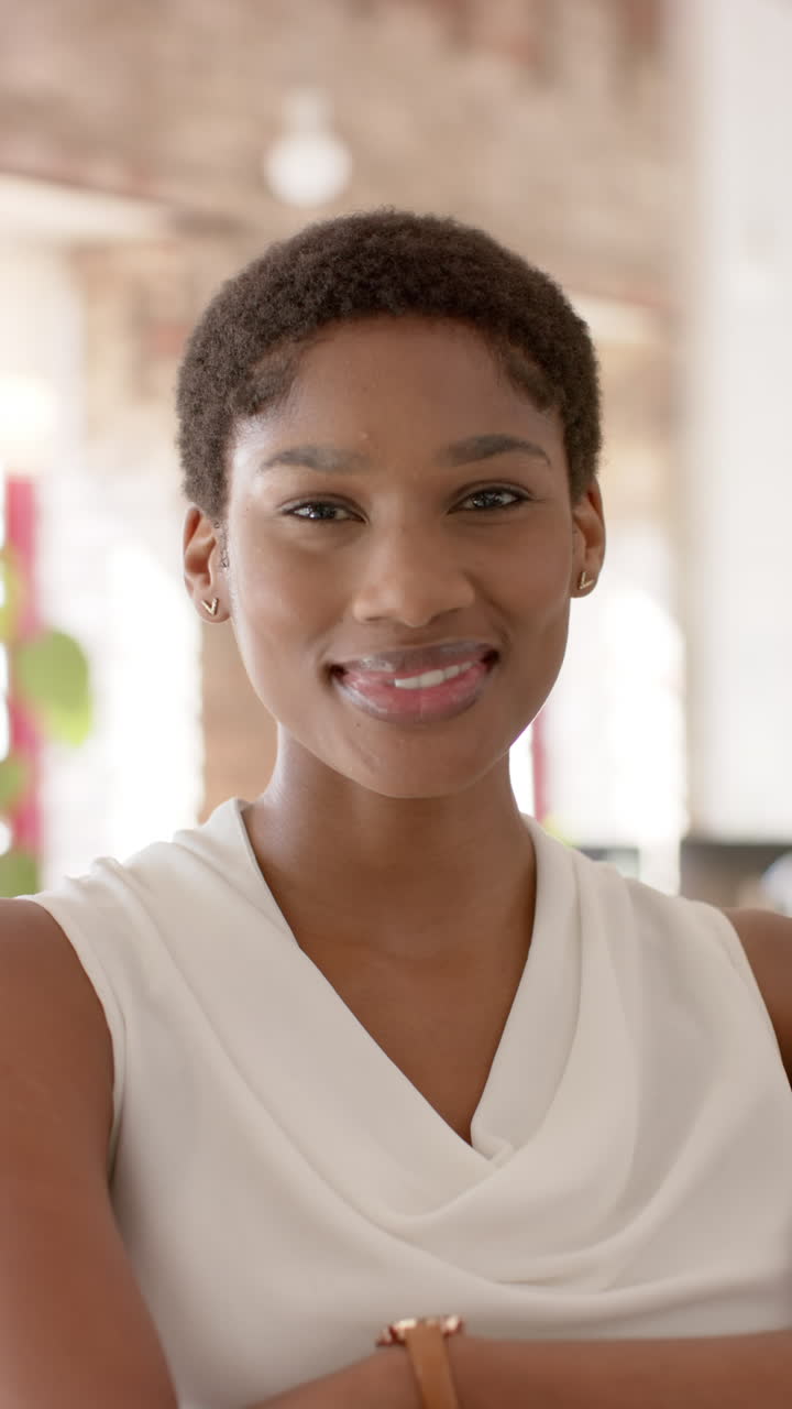 Vertical video of portrait of happy african american casual businesswoman in office in slow motion