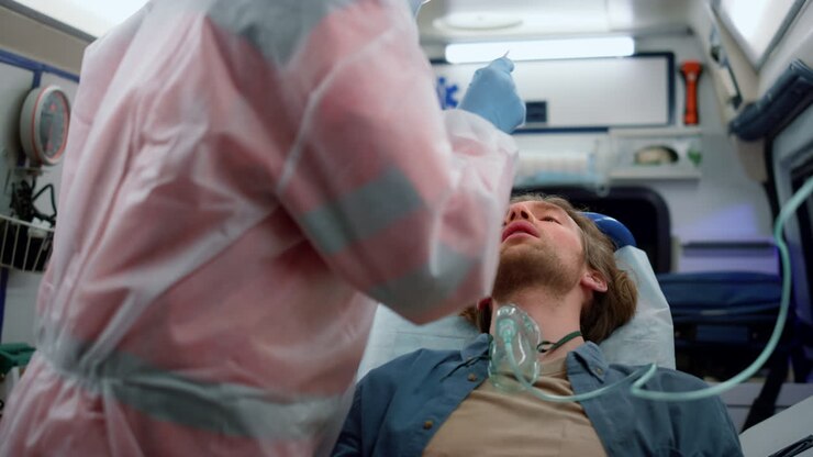 Squadra di paramedici che esegue un tampone nasale per coronavirus su un uomo in ambulanza.
