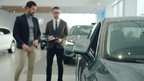 car salesman showing a car to a customer in a showroom