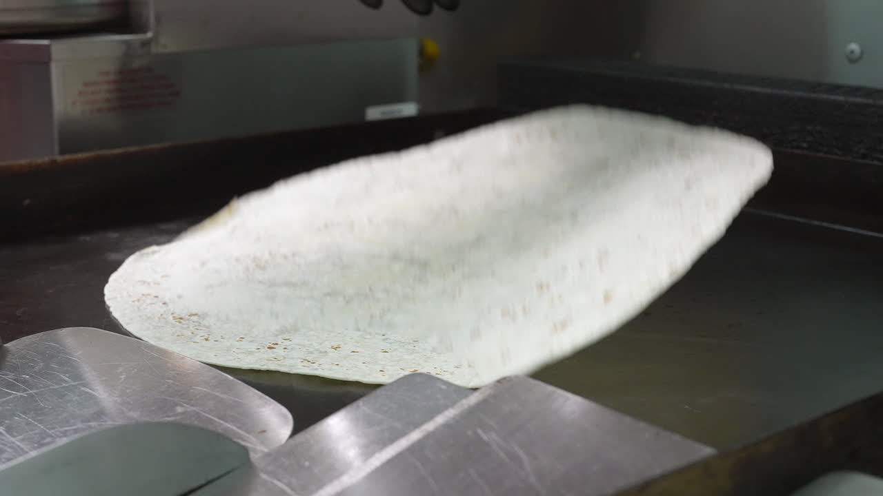 Flipping a hot flour tortilla on the flat top griddle - food truck series