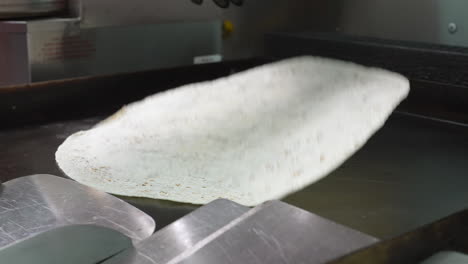 volteando una tortilla de harina caliente en la plancha superior plana - serie de camiones de comida