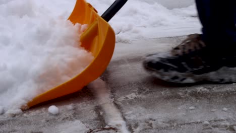 una pala de nieve de plástico limpiando la nieve de un camino de entrada