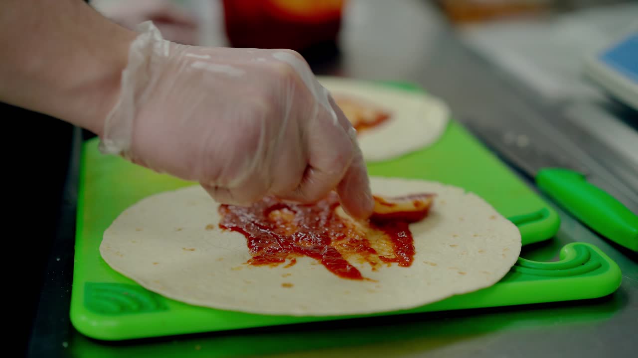Cook prepares the wok smears the red sauce over the cake