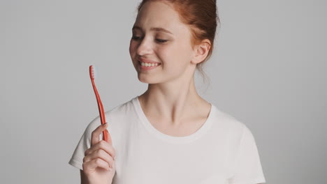 redheaded girl in front of camera on gray background.