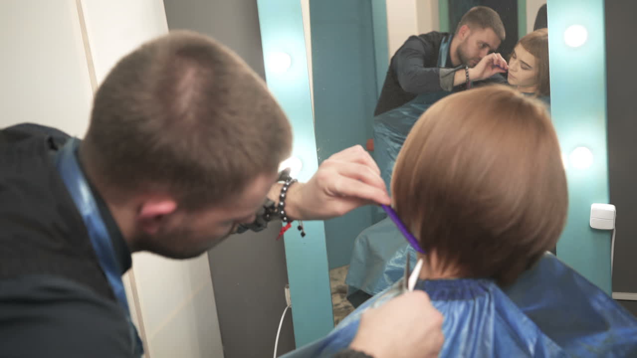 Hairdresser cutting hair of her customer at the hairdressing salon