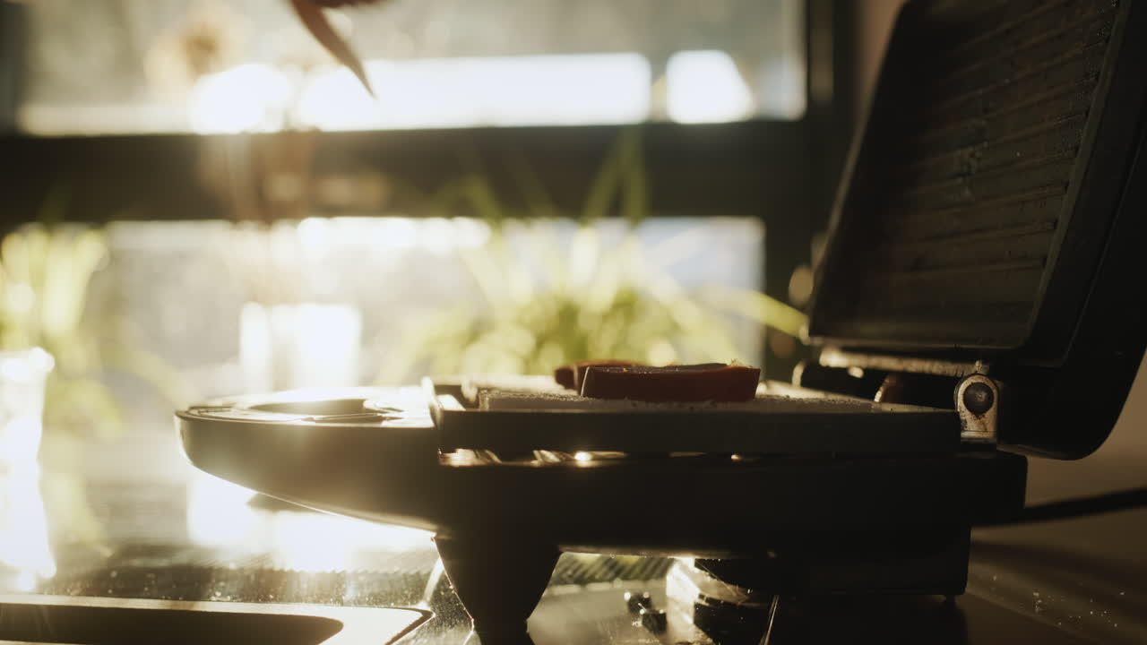 전기 샌드위치 메이커 에서 뜨거운 샌드위치 를 준비 하는 여자