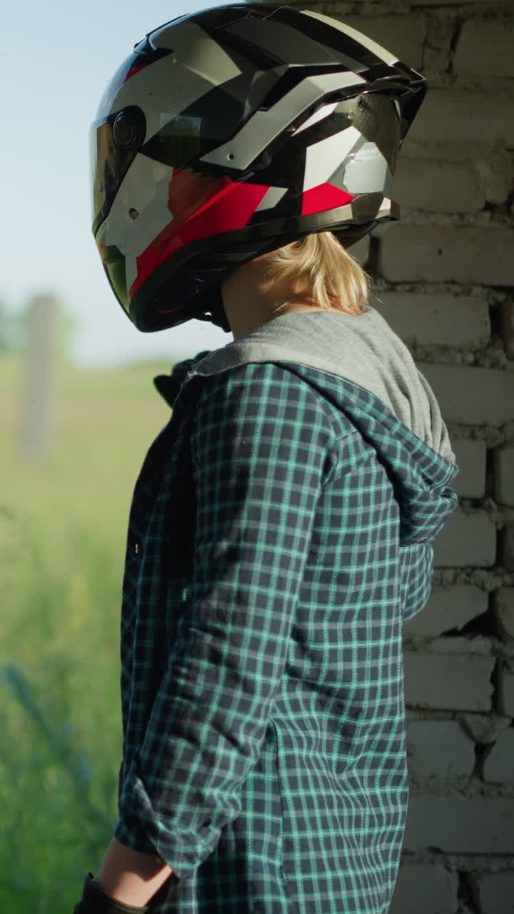 dos amigos con cascos de pie dentro de un edificio abandonado mirando hacia un campo, una amiga mira hacia el campo mientras que la otra mira hacia los lados a su compañero