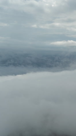 vertical 4k timelapse of clouds and dense fog moving above high mountain peaks