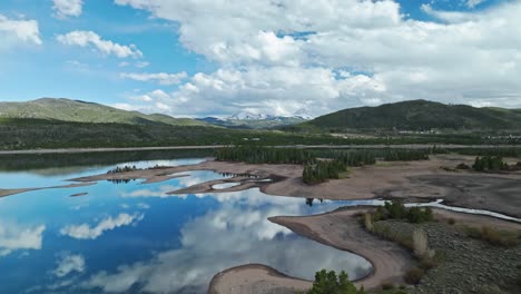 Aerial-dolly-above-Dillon-reservoir-reflecting-cloudy-blue-sky-in-calm-water-in-Frisco-Colorado