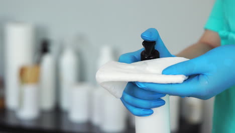 close - up of gloved hands apply skin care product on a napkin in the beauty salon