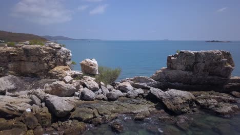 antena: un vuelo hacia atrás a baja altura que revela una abertura entre las rocas altas y vuela ligeramente por encima de ella sobre el océano azul celeste