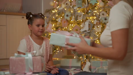 Little-Girl-And-Mother-Exchange-Christmas-Gifts-At-Home