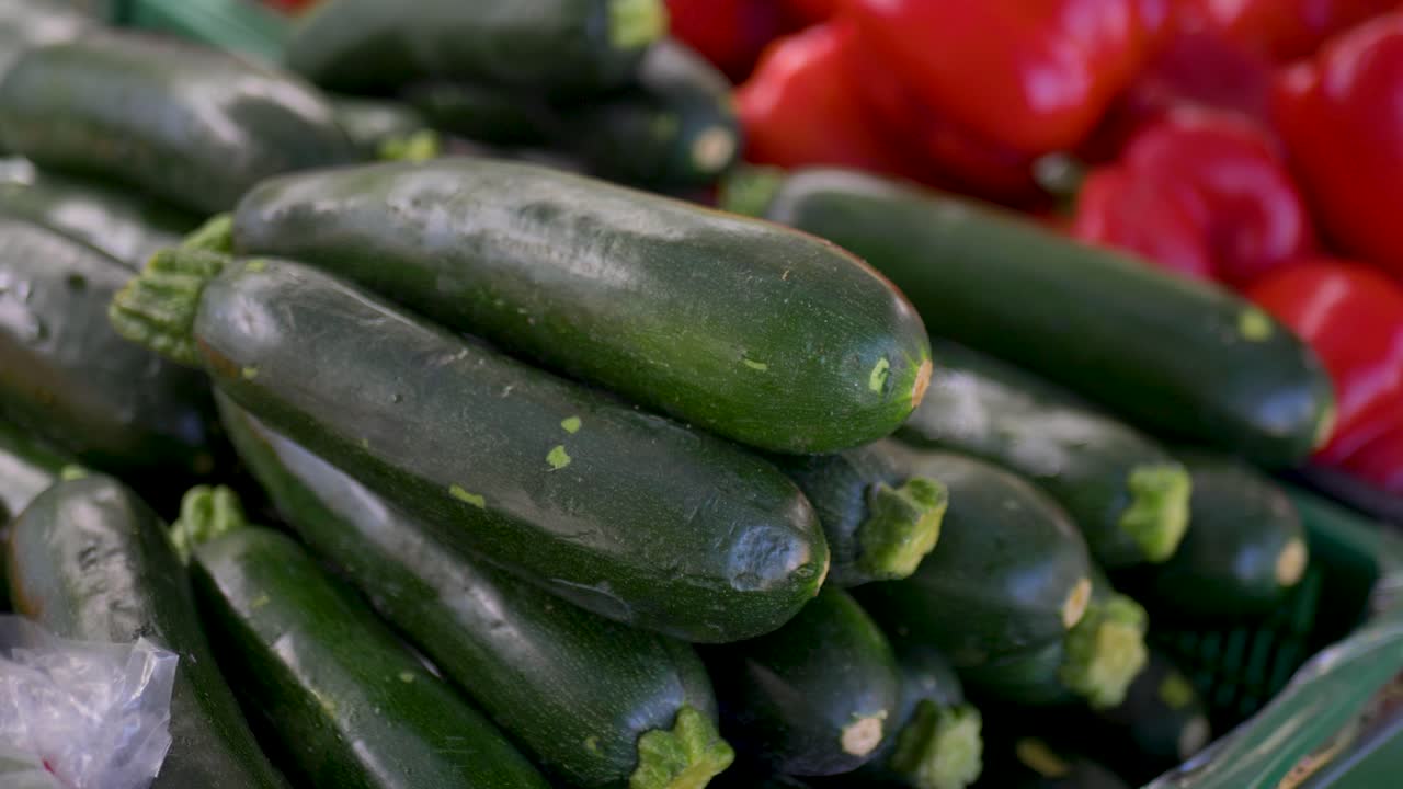 Slow motion close up of a bundle of fresh and organic zucchinis with capsicum vegetables in a basket at a local farmer's market food and produce stall in Sydney Australia nutrition and healthy eating