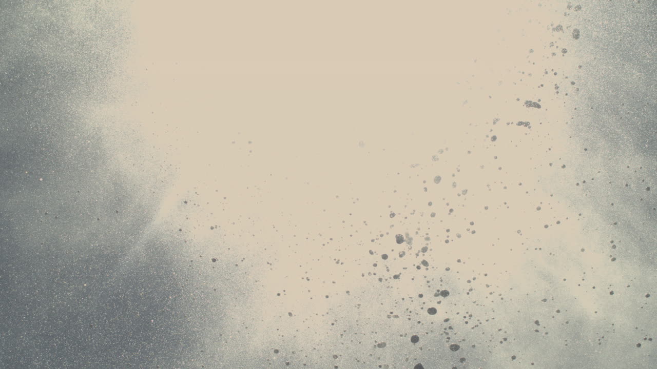 White spray from blowhole erupts with mist and foam particles flying high into blue sky