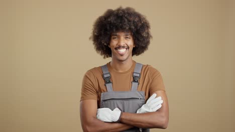 a smiling man in work overalls and gloves with an afro