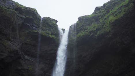 A-waterfall-in-Iceland,-surrounded-by-tall-cliffs---Slow-motion