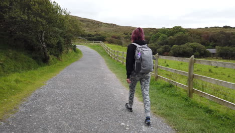 dolly shot of a girl walking, hiking in connemara national park on the trail to diamond hill in ireland 4k