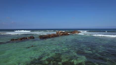 drone shot passing over rocks at anse forbans beach mahe seychelles