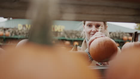 Woman-picking-pumpkins-at-Halloween-agricultural-fair