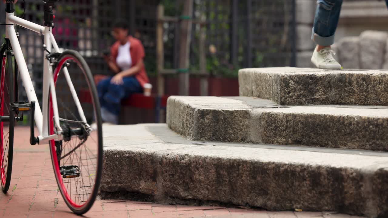 Kerumunan beragam melewati tangga plaza, kaki bersneaker masuk, pengendara sepeda yang terburu-buru, wanita yang duduk dengan cangkir menunggu