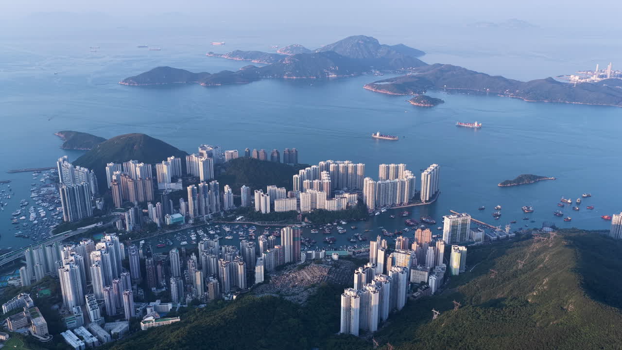 Cinematic aerial view of Hong Kong skyline shrouded in mist at blue hour, with glowing skyscrapers and Victoria Harbour fading into a moody, atmospheric twilight