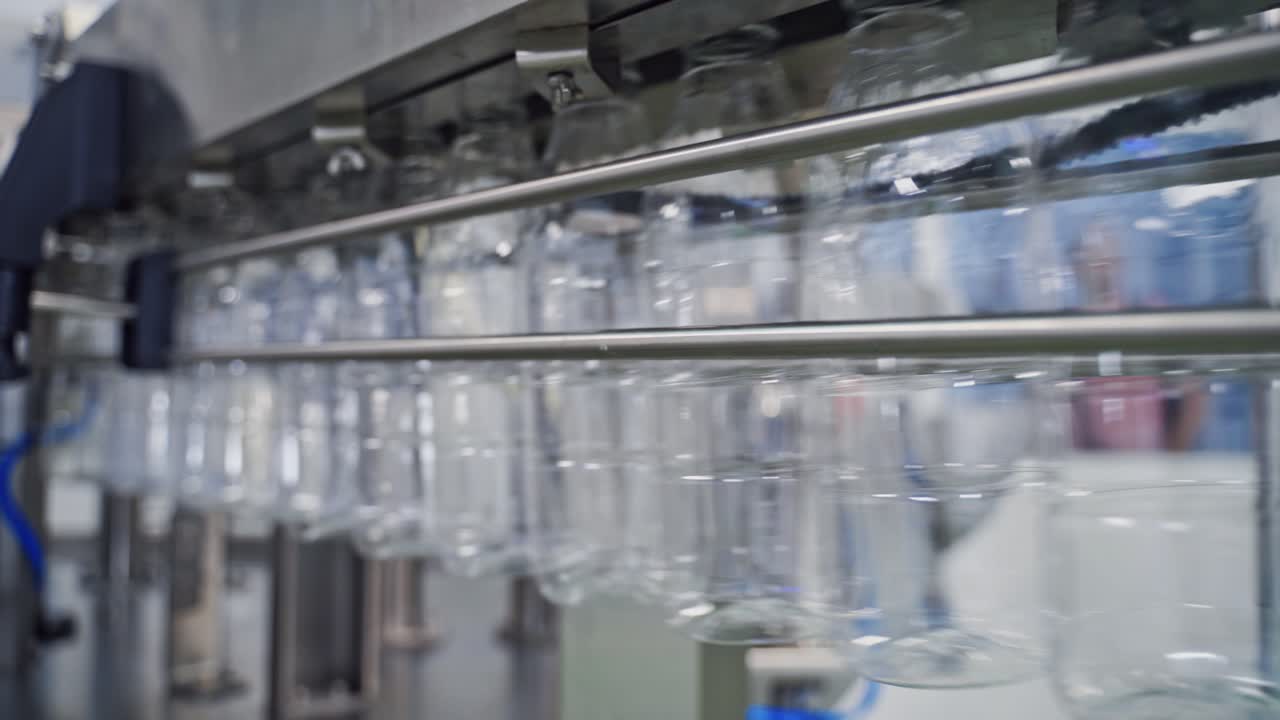 Pure transparent bottles on a conveyor belt. Conveyor with clean empty bottles at big factory. Plastic bottles moving on manufacturing line in a modernized plant.