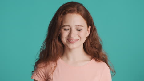 redheaded girl in front of camera on turquoise background.