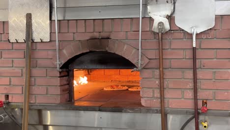 la pizza se hornea en el horno tradicional de ladrillo caliente con llama de fuego directo