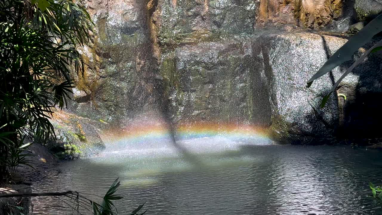 un arco iris se forma sobre una cascada serena