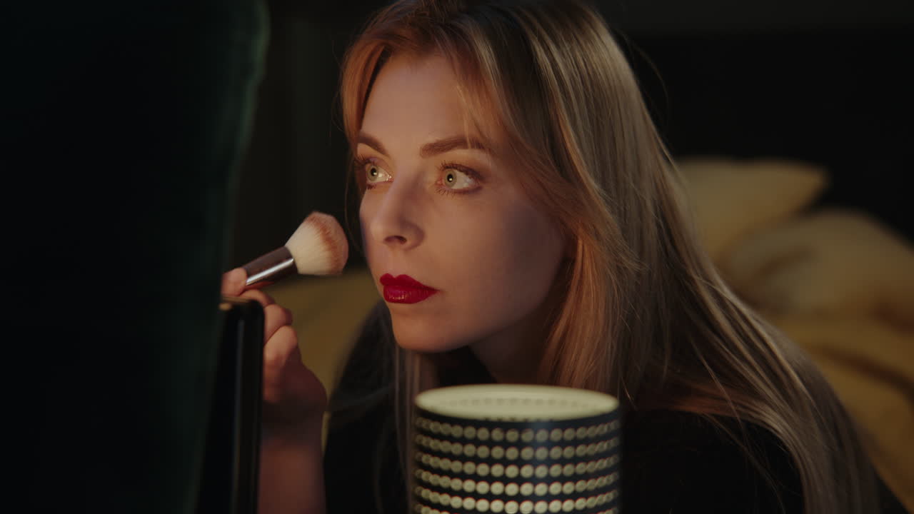 Woman applying makeup at night