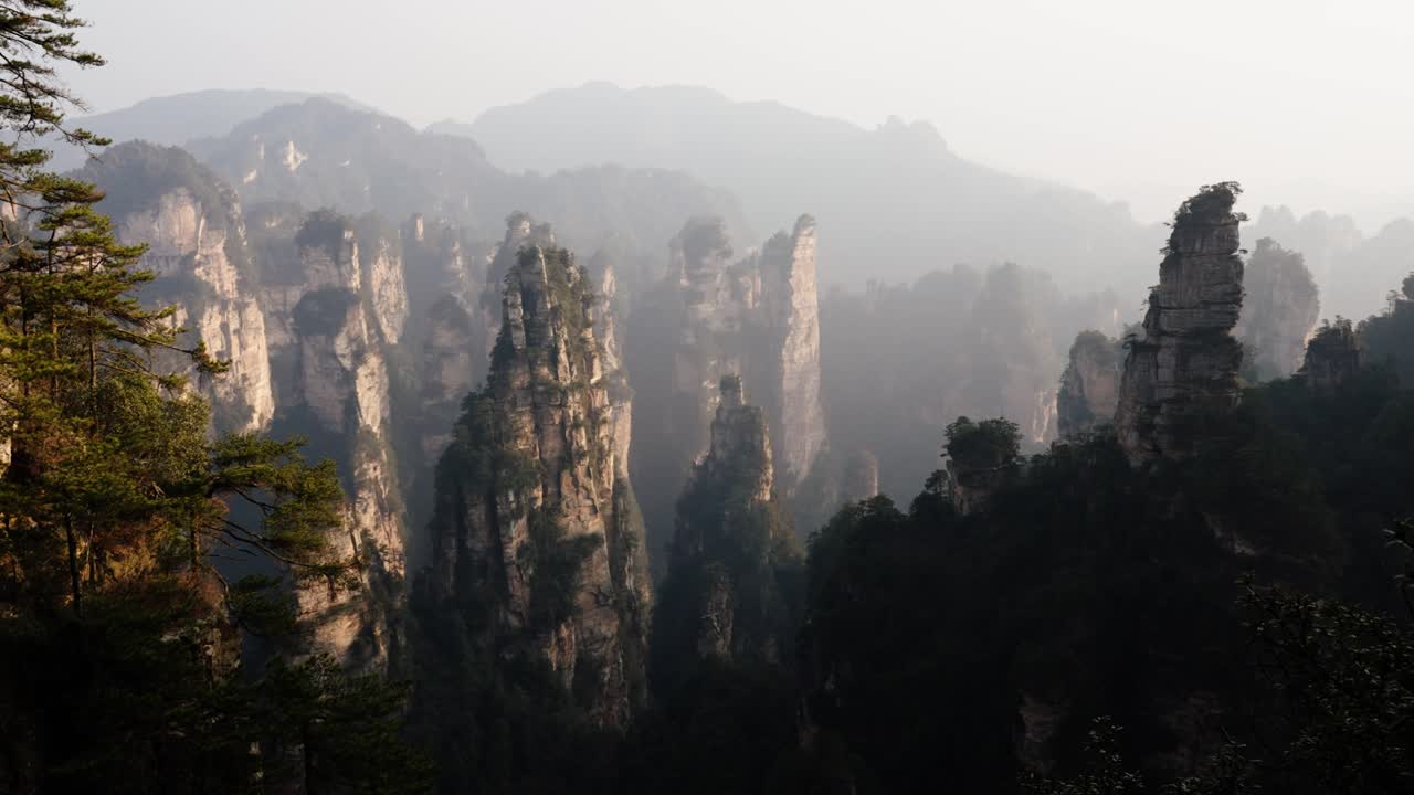 Sandstone towers rise through mist and forest in Zhangjiajie National Park, surrounded by dramatic cliffs and lush vegetation