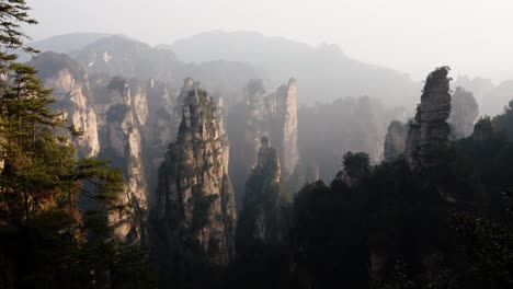 sandstone towers rise through mist and forest in zhangjiajie national park, surrounded by dramatic cliffs and lush vegetation