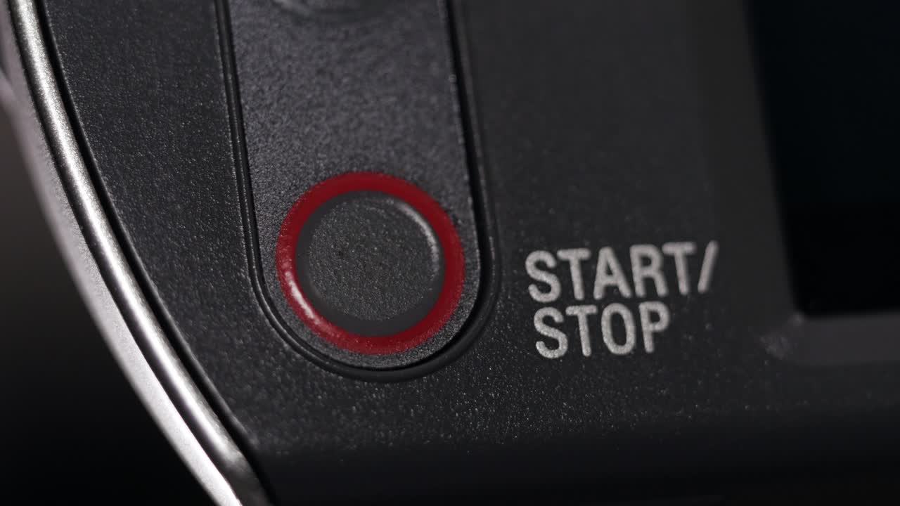 Macro close up of finger pressing red Start Stop button on silver camcorder flip screen