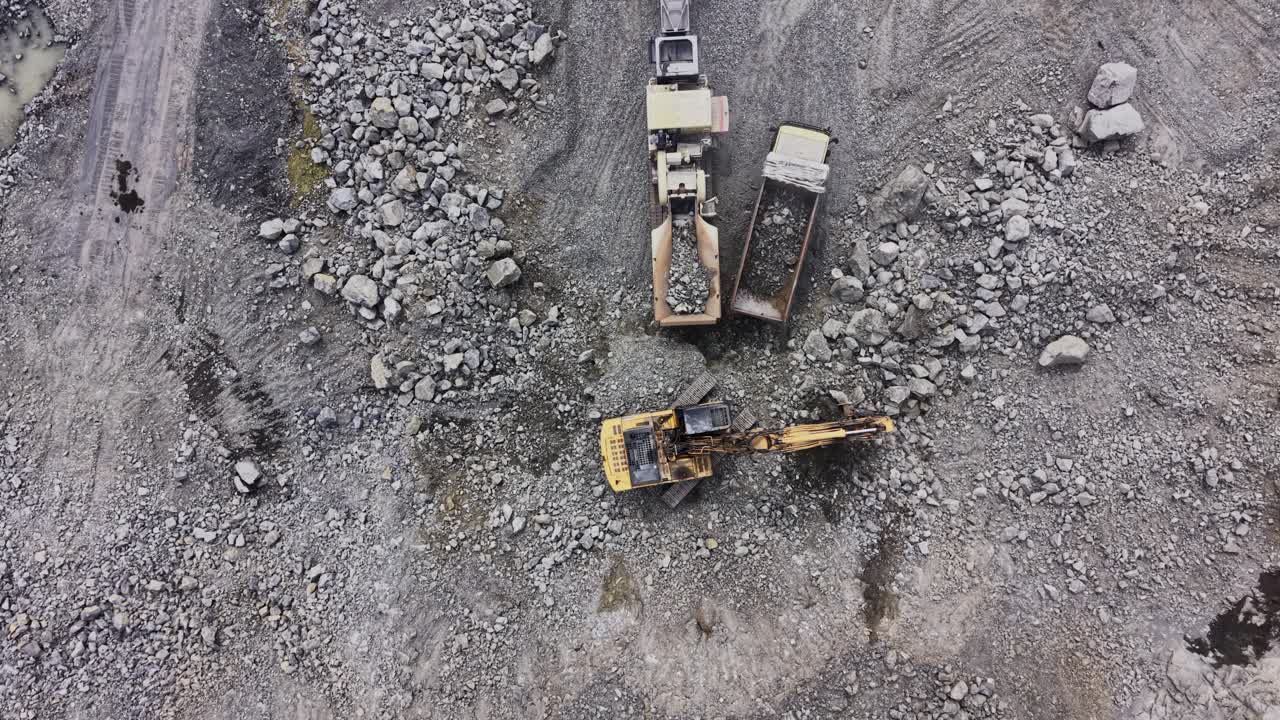 Aerial Top-Down View of Excavator Loading Rocks into Dump Truck at Quarry
