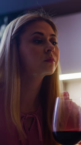 una dama de bajo nivel vierte un producto venenoso en un vaso de vino con vino tinto preparando una cena mortal en la cocina en close-up en cámara lenta.