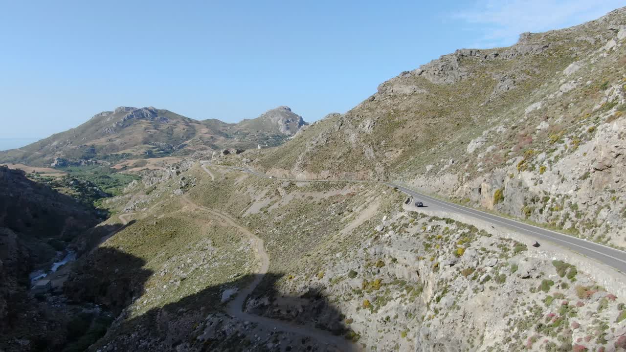 Wide angle dolly in aerial drone shot of beautiful mountains, hills , valleys , roadways, and walkways in west Crete islands, preveli beach during the day