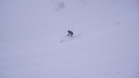 a man driving a snowmobile jumping on a snowed hill in slow motion