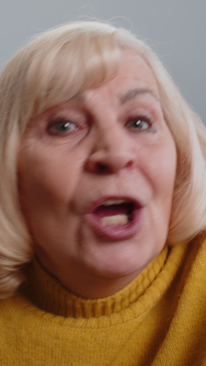 Punto di vista: anziana nonna fa una videochiamata online, parla, saluta con la mano e guarda la telecamera.