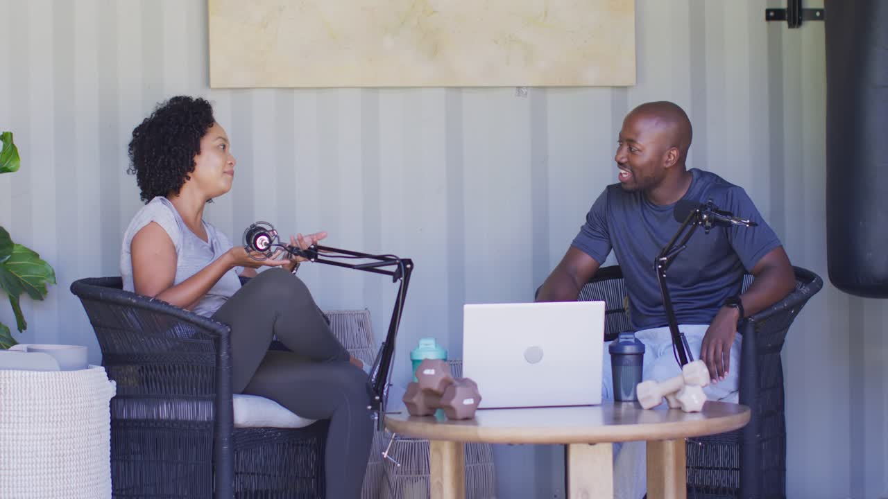 African American hosts chatting after woman starting comment, recording in studio with mics and PC