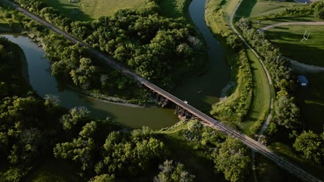 aerial view rotating around gorgeous snake river with green terrain and forest with railroad track across the river