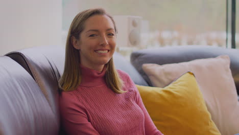 portrait of smiling woman relaxing on sofa at home
