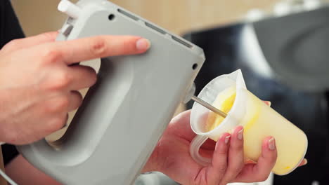 el chef bate la yema de huevo dentro de un vaso de plástico con una batidora, haciendo café con huevo vietnamita