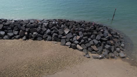 Water-Breaker-Rocks-To-Protect-Coastline-Erosion-At-Elmer-Sands-Beach-In-West-Sussex,-UK---aerial-sideways